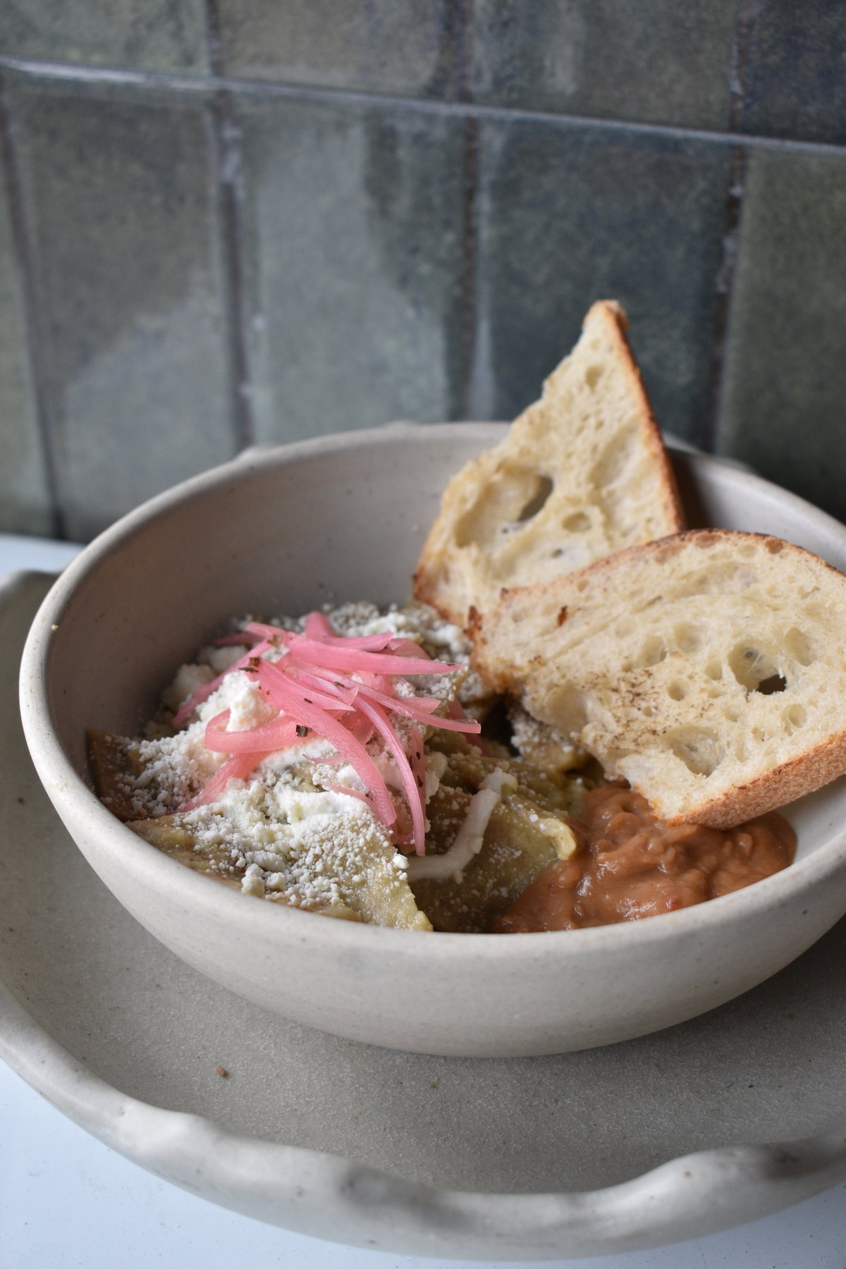 Chilaquiles verdes con frijoles, queso y cebolla encurtida